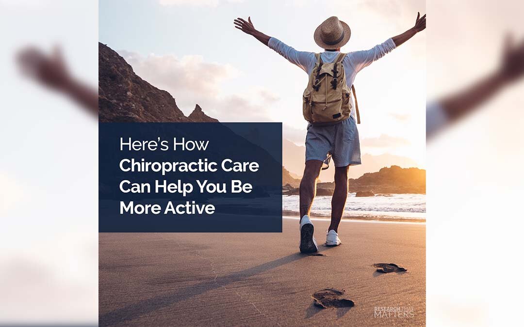 A man stands on the beach with arms open wide up to the sky, happy to be more active because of chiropractic care.